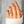 Hand wearing a gold ring with a snake design against a neutral background