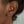 Close-up of an ear wearing gold hoop earrings with a blurred background