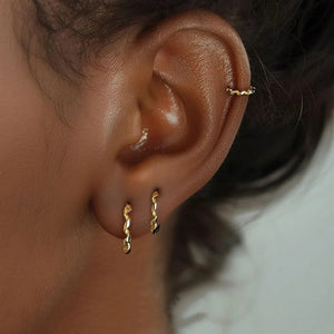 Close-up of an ear wearing gold hoop earrings with a blurred background