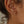Close-up of an ear wearing gold hoop earrings with a neutral background