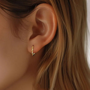 Close-up of an ear wearing a gold hoop earring with blonde hair.
