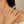 Close-up of a hand wearing two gold rings on a neutral background