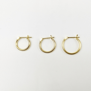 Three gold hoop earrings on a light gray background
