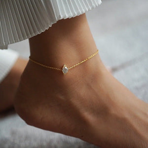 A gold-plated sterling silver anklet featuring a marquise diamond, displayed on a person's ankle.