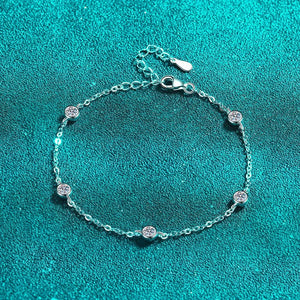 Silver bracelet with small round charms on a teal background