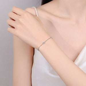 Silver bracelet on a person's wrist against a neutral background