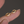 Gold hoop earrings with small diamonds on a finger against a dark background