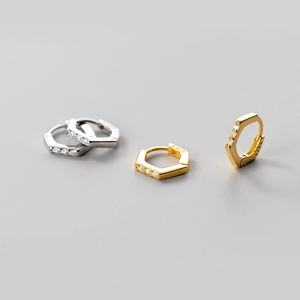 Three gold and silver hoop earrings on a gray background