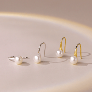 Pearl jewelry set with silver and gold earrings on a beige background