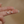Gold earrings with small crystals held between fingers against a beige background