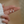 Silver earrings held between fingers against a blurred background