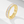 Gold ring with clear gemstones on a light gray background