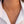 Gold necklace with small round pendants on a person wearing a white shirt.