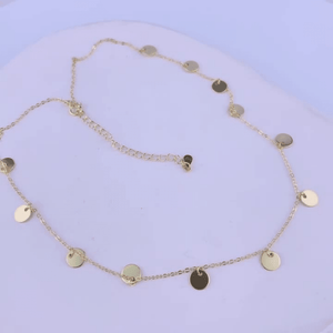Gold necklace with round pendants on a light purple background