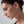 Close-up of a woman wearing a gold earring against a neutral background