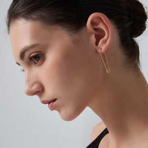 Close-up of a woman wearing a gold earring against a neutral background