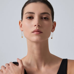 Close-up of a woman wearing gold hoop earrings against a plain background