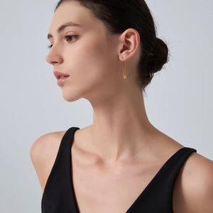 Woman wearing a gold earring against a plain background