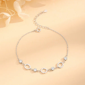 Silver bracelet with circular and floral designs on a beige background