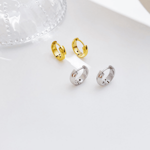 Three hoop earrings in gold, silver, and rose gold on a white surface.