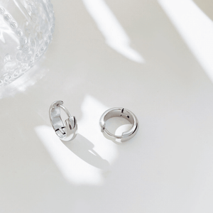 Silver hoop earrings on a light gray surface