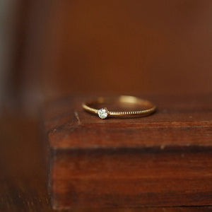 Gold ring with a diamond on a wooden surface