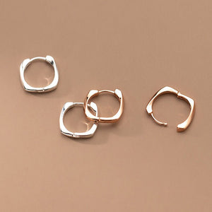 Three hoop earrings in silver and rose gold on a beige background