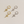Two pairs of star-shaped earrings, one gold and one silver, on a light beige background.