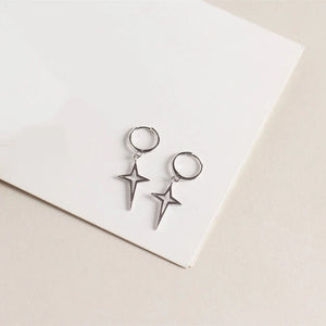 Silver star-shaped earrings on a white card with a beige background
