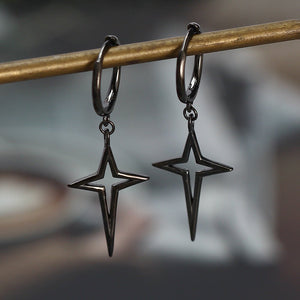 Star-shaped earrings hanging from a branch with a blurred background