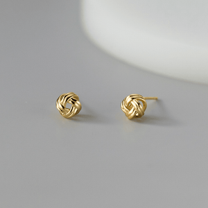 Pair of gold knot earrings on a gray background