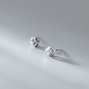 Silver knot earrings on a gray background