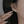 Close-up of an ear wearing a silver earring with a hand holding another similar earring.