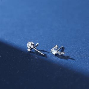 Two silver earrings with gemstones on a blue background