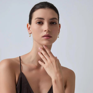 Woman wearing gold earrings with a neutral background