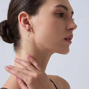 Close-up of a woman wearing gold earrings with a neutral background