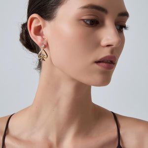 Close-up of a woman wearing gold earrings with a gray background