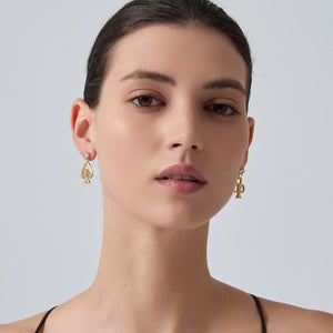 Woman wearing gold earrings against a plain background