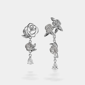 Silver rose-shaped earrings with teardrop drops on a white background