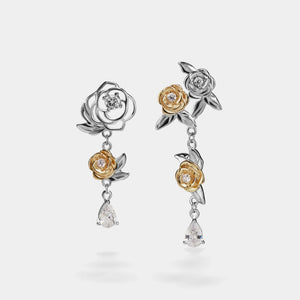 Pair of floral earrings with gold and silver accents on a white background