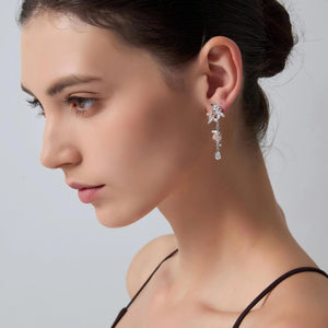 Close-up of a woman wearing elegant earrings against a neutral background