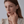 Model wearing a gold stud earring featuring conch shell design
