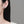 Close-up of a person wearing a diamond earring on a plain background