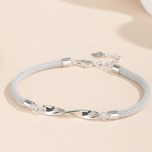 Two Mobius infinity couple matching bracelets, one with a black cord and silver ends, and the other with a white cord and silver ends, displayed against a neutral background.