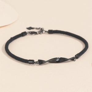 Two Mobius infinity couple matching bracelets, one with a black cord and silver ends, and the other with a white cord and silver ends, displayed against a neutral background.