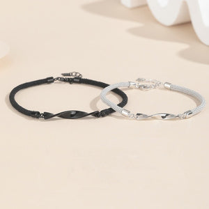 Black and silver braided bracelets on a beige surface