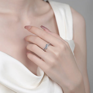 Hand wearing a silver ring with a diamond design against a neutral background