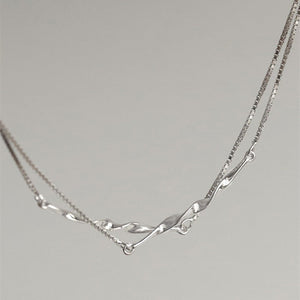 Silver necklace on a light gray background