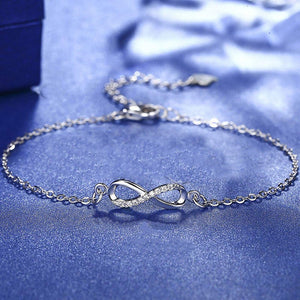 Silver infinity bracelet on a blue textured surface