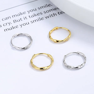 Two pairs of hoop earrings, one gold and one silver, on a magazine page.
